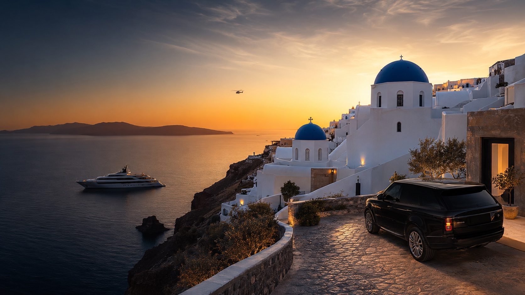 Black Range Rover overlooking Santorini at sunset with a superyacht offshore and helicopter in the sky